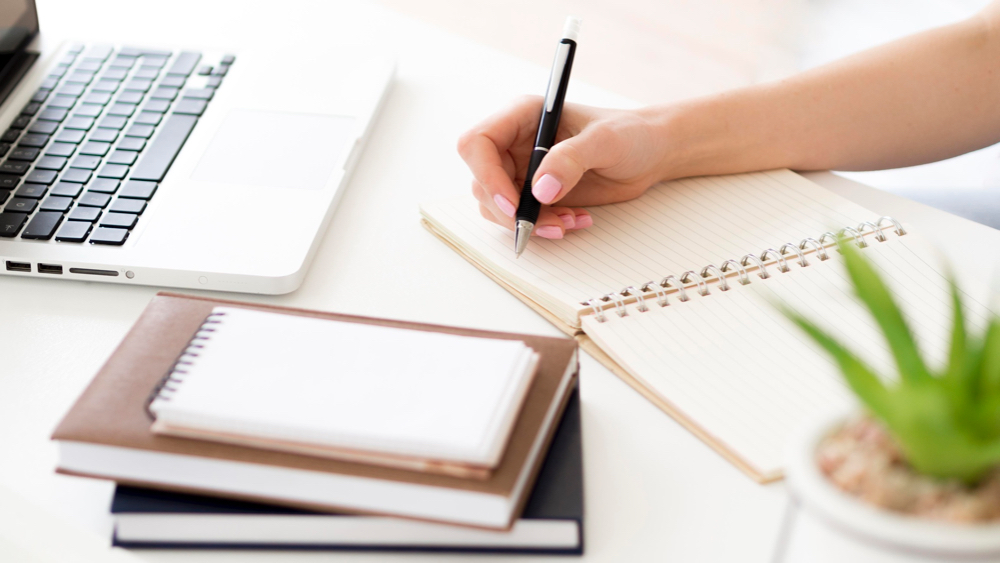 high view person writing on notepad
